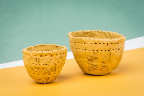 Kaks käsitööna tehtud savikaussi erineva suurusega, mille pinnal on jooned ja punktid dekoratiivsete motiividega.